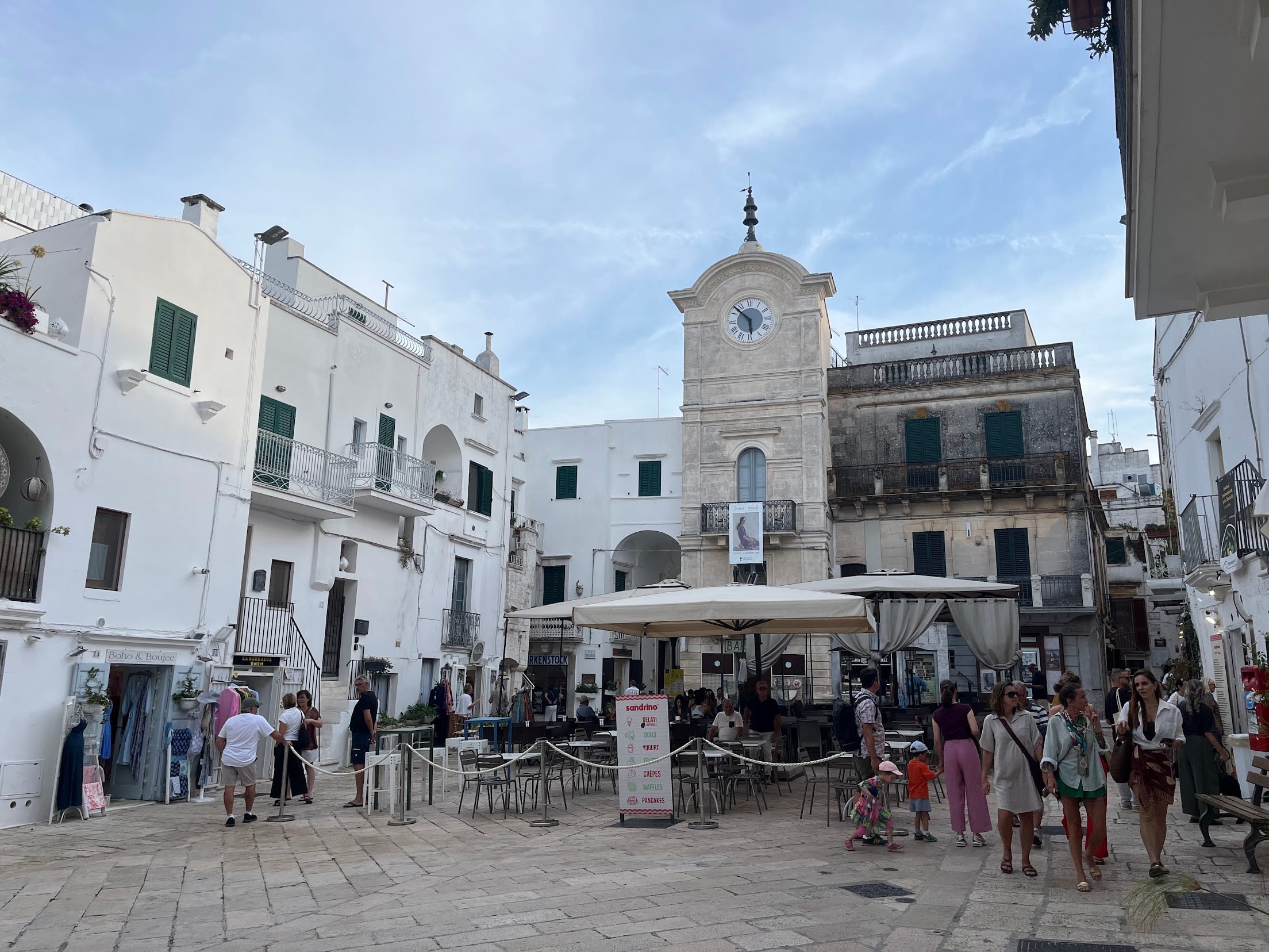 The main square in Cisternino, with the clock tower and cafe terraces surrounded by whitewashed buildings